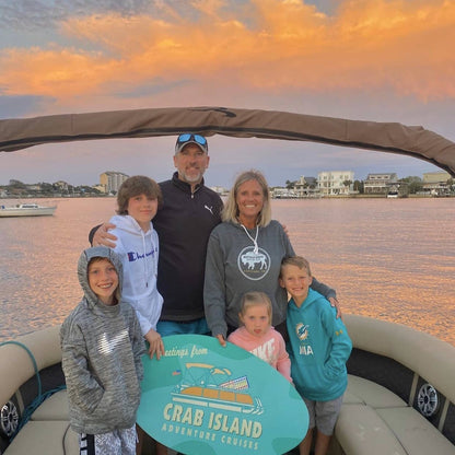 Family taking a picture on a private boat charter with the sunset in the background